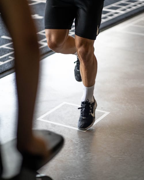 Beine eines Sportlers beim Sprinttraining auf dem markierten Boden