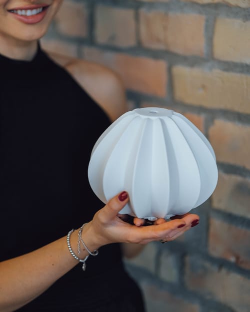 Der Aromadiffuser liegt auf einer ausgestreckten Hand vor einer Backsteinwand