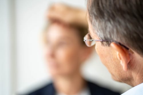 Detailaufnahme über die Schulter eines Mannes mit Brille, das Gegenüber unscharf im Hintergrund